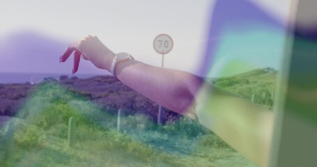 Extending woman's arm out window into road with red nails silver wristwatch, speed sign showing 70