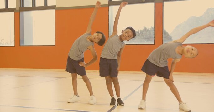 Performing side bends three boys in matching athletic attire in school gym, with sports court lines - Powered by Adobe