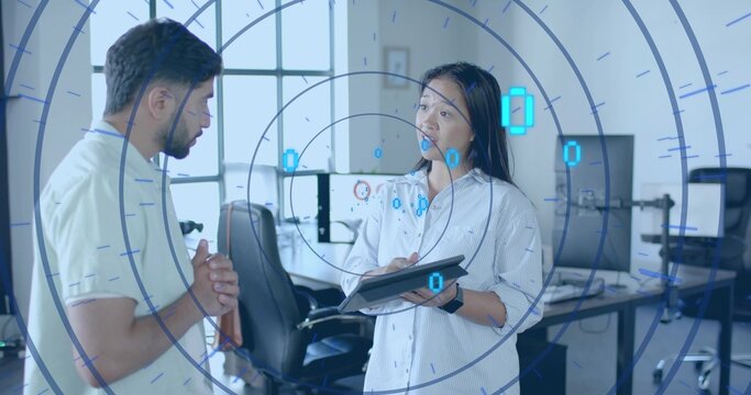 Discussing data trends two colleagues using tablet and monitors in tech office, with AR overlay