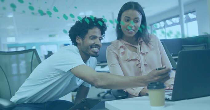 Pointing man holding stylus and tablet consulting woman at open-plan office with laptop and coffee - Powered by Adobe