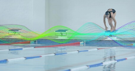 Swimmer wearing black swimsuit and goggles climbing starting block poolside, lane ropes, copy space