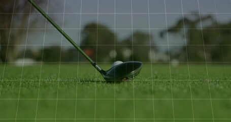 Positioning golf driver head behind golf ball on fairway turf, with tree-lined background