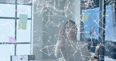 Sketching Asian woman drawing network diagrams on glass board in conference room, with white marker