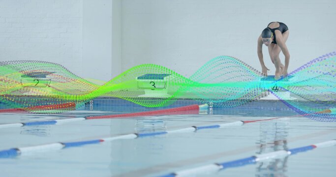 Swimmer wearing black swimsuit and goggles climbing starting block poolside, lane ropes, copy space - Powered by Adobe