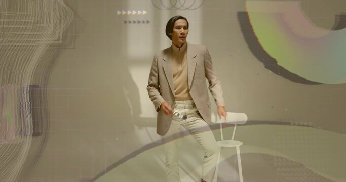 Posing Asian model wearing neutral blazer in studio with abstract projections, holding camera lens