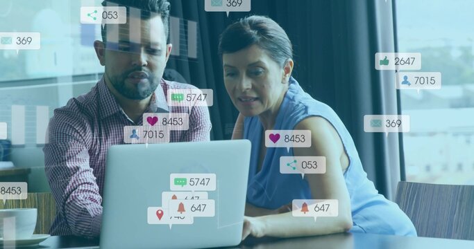 Analyzing social media icons colleagues leaning over silver laptop at office with coffee cup