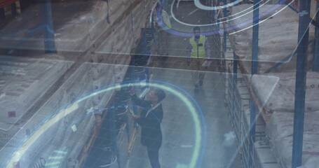 Scanning logistics manager in dark suit using handheld scanner inside warehouse with racks