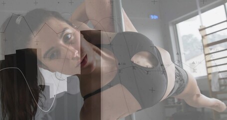 Woman wearing black sports bra briefs performing pole inversion in dance studio with window barre