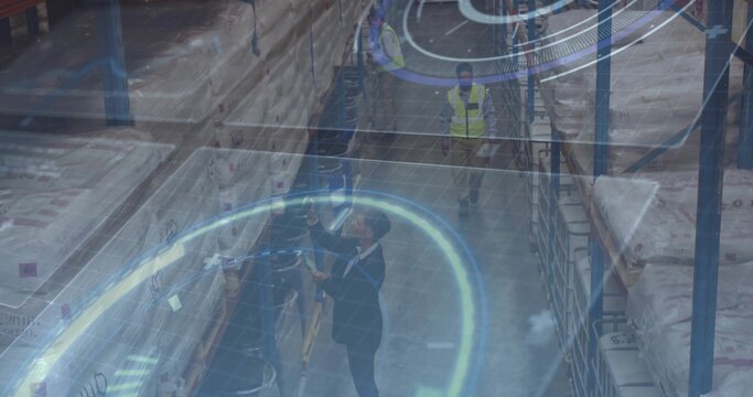 Scanning logistics manager in dark suit using handheld scanner inside warehouse with racks