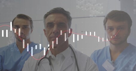 Doctor and nurses analyzing candlestick overlay in clinic corridor, with stethoscope, scrubs