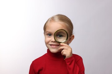 Little girl with magnifying glass on white background