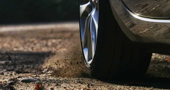 Slow Motion lose-up of a car wheel spinning and kicking up dust on a dirt road. Dynamic slow-motion footage capturing power and movement a1000 fps.