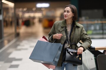 Woman with different shopping bags in mall, space for text