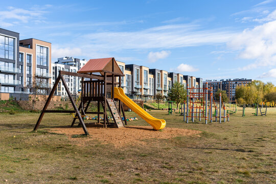 Children's playground with wooden structure and slide near modern apartment buildings
