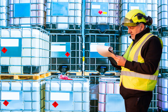 Warehouse inspector checks documents near chemical containers, industrial safety supervision and control of hazardous materials storage.