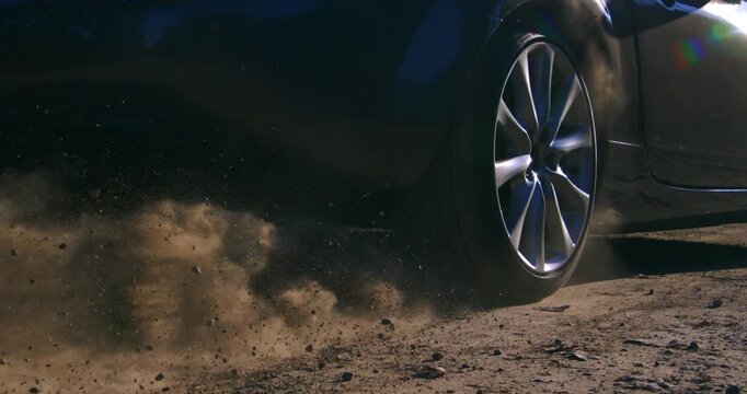 Slow motion of a car wheel spinning and kicking up dust on a dirt road. Dynamic slow-motion footage capturing power and movement a1000 fps.