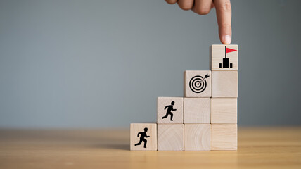Minimalist photograph of stacked beige wooden blocks with icons, finger touching top block, symbolizing personal growth, career success, ambition, and achievement, soft side lighting.