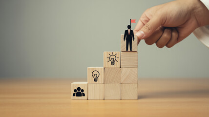Creative business growth concept with wooden blocks forming upward staircase, teamwork and leadership icons, hand placing final block, symbolizing success, vision, motivation, and strategy.