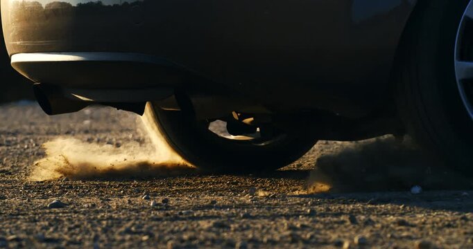 Slow motion close up of car wheel accelerating on gravel terrain, lifting dust and debris at 1000 fps.. Perfect for concepts of adventure, energy, and motion.