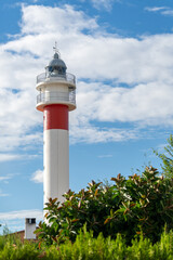 The top of the El Rompido lighthouse in Huelva stands out against the blue sky and white clouds.