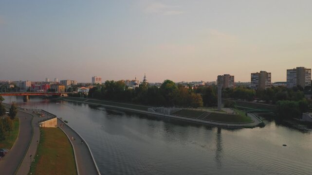 Aerial evening view of Orel city in Russia with river, Strelka, main buildings, churches and roads. Beautiful cityscape with lights reflecting on water at sunset, showing urban architecture, skyline.