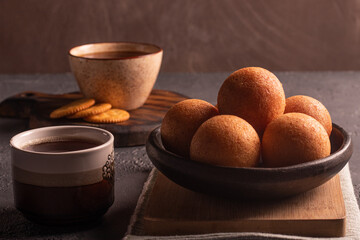 Traditional Colombian buñuelo-fritter with coffee – rustic Latin American breakfast in warm low key lighting