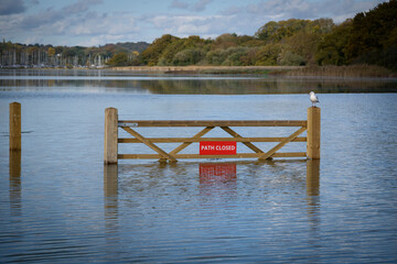 Flooded footpath blocked by a wooden gate and a red 'Path Closed' sign