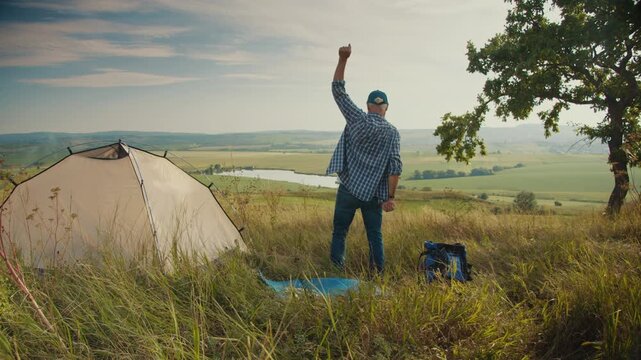 Spiritual Joy, Grateful Living, Faith in Nature. Senior Man Stands Beside His Tent, Arms Raised in Praise, Surrounded by Majestic Mountains. A Moment of Worship, Gratitude, and Celebration