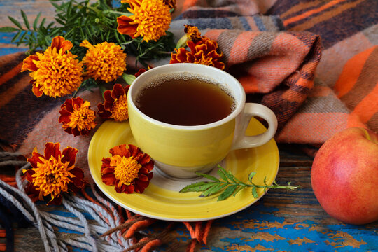Autumn Tea Party: A yellow cup of tea with autumn flowers against a brown shawl