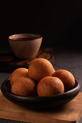 Traditional Colombian buñuelo-fritter with coffee – rustic Latin American breakfast in warm low key lighting