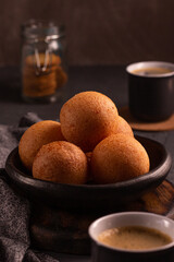 Traditional Colombian buñuelo-fritter with coffee – rustic Latin American breakfast in warm low key lighting