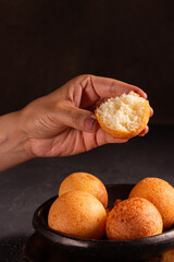 Colombian buñuelo-fritter held by hand – traditional Latin American snack with rustic background and warm lighting