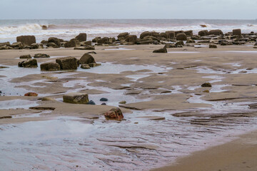 Tidal pools form between weathered rocks on deserted coastline at Spurn Head, Yorkshire, UK.