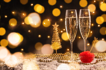 Two glasses of champagne with red caviar on festive golden bokeh background, elegant New Year...