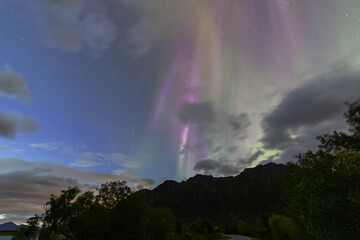 The stunning Northern Lights over Lofoten Islands, Norway, with vivid colors lighting up the night sky above mountains.
