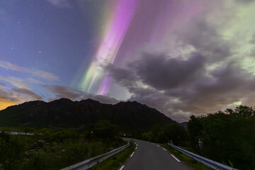 The stunning Northern Lights over Lofoten Islands, Norway, with vivid colors lighting up the night sky above mountains.