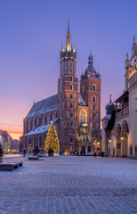 St Mary's church and Cloth Hall fragment on snow covered Main Square in winter Krakow, illuminated in the dawn