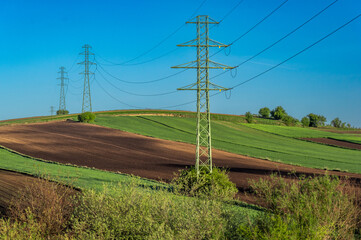 Overhead power line with conductors suspended by towers, rural area of Ponidzie, Poland