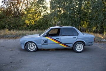 Vintage gray rally car with racing stripes and number 30 parked outdoors