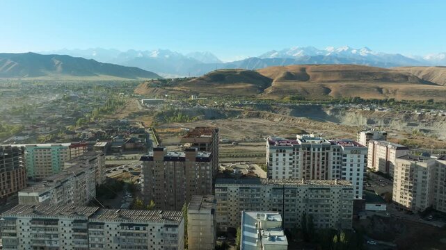 Bishkek aerial video, flying backwards on the outskirts of Microdistrict 11 with beautiful Tian Shan mountain scenery in the background.