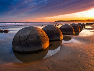 Spheric moeraki boulders on the koekohe beach in New Zealand at sunset. Design for travel magazines, publications, advertising, marketing, posters, wall art, digital wallpapers, social media, blogs