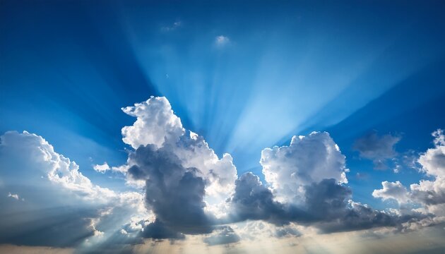 thick and billowy clouds against a brilliant blue sky with multiple sun rays peeking through soft sky