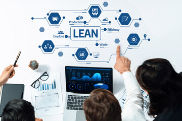 A diverse business team collaborates over charts and technology, focusing on lean methodology to...