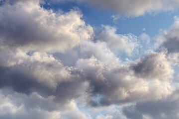 Obraz premium Fluffy clouds against a serene sky in shades of grey, white, and blue, evoking calmness and tranquility in a peaceful landscape. Perfect for nature-themed projects and serene backgrounds