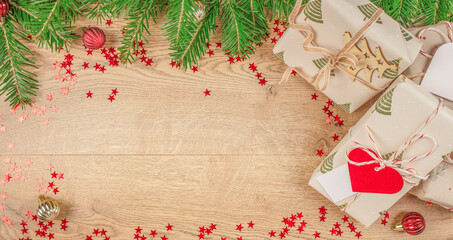 Christmas gifts wrapped in eco paper with fir branches, red confetti stars, and festive ornaments...