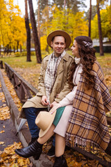 Charming couple enjoying a cozy moment outdoors in a city park during autumn. They share a joyful smile, conveying warmth and connection on a sunny day.