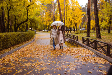 Charming couple enjoying a cozy moment outdoors in a city park during autumn. They share a joyful smile, conveying warmth and connection on a sunny day.
