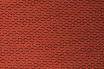 Close up of a textured orange sports mesh fabric with a small repeating pattern