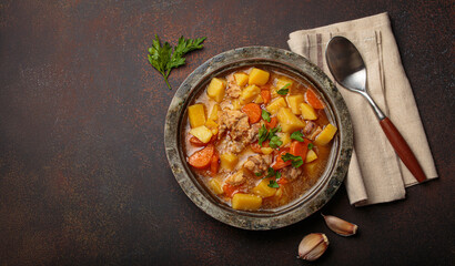 Hot chicken stew or soup with tender chicken pieces, chunky potatoes, and vibrant carrots garnished with fresh parsley in rustic bowl, comfort food for autumn and winter, copy space