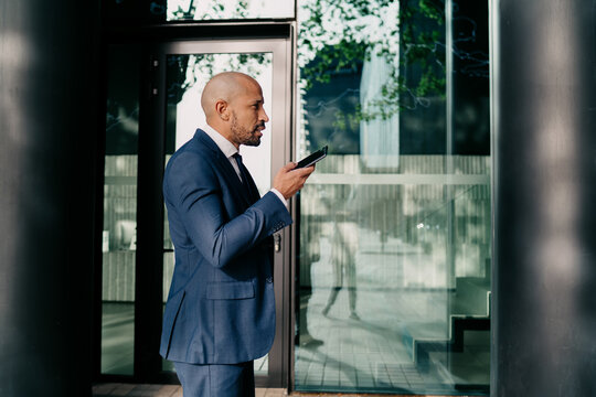 Businessman speaks clearly into smartphone using voice function, showing command, focus, and the integration of AI-powered mobile tools into professional communication. - Powered by Adobe
